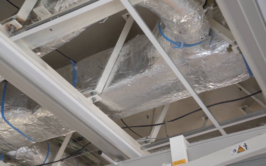 Luchtkanaal met zilveren isolatie en blauwe tape.