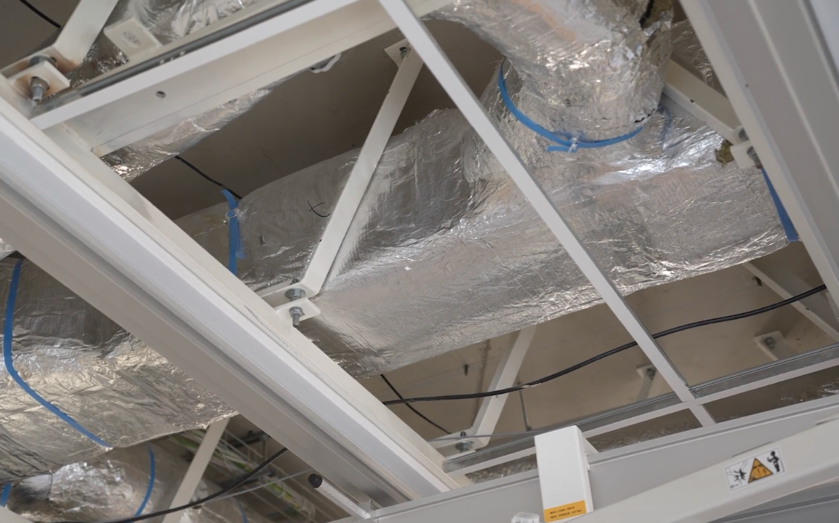 Luchtkanaal met zilveren isolatie en blauwe tape.