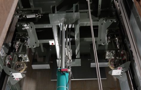 Interieur van een liftmachinekamer met kabels en wielen.