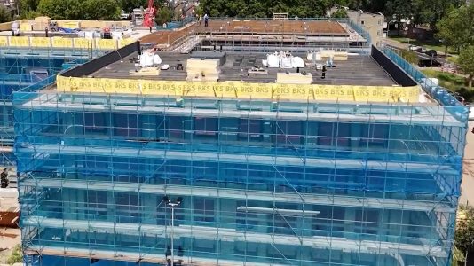 Gebouw in aanbouw met blauwe steigers.