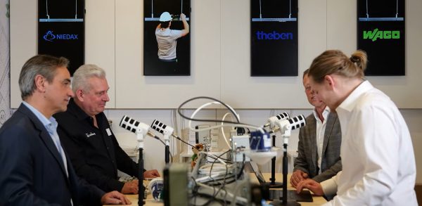 Mannen aan tafel met microfoons en technische apparatuur.