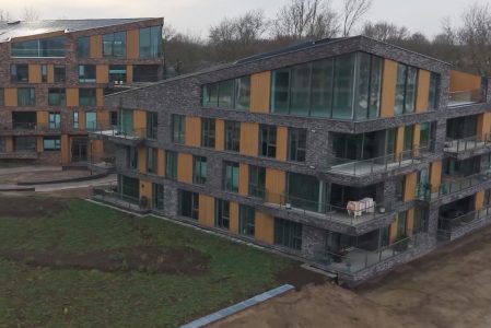 Modern appartementencomplex met glazen gevels en balkons.