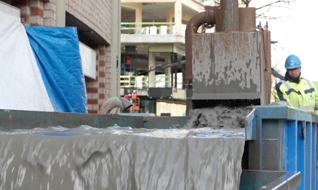 Cementstort bij bouwplaats met arbeider.