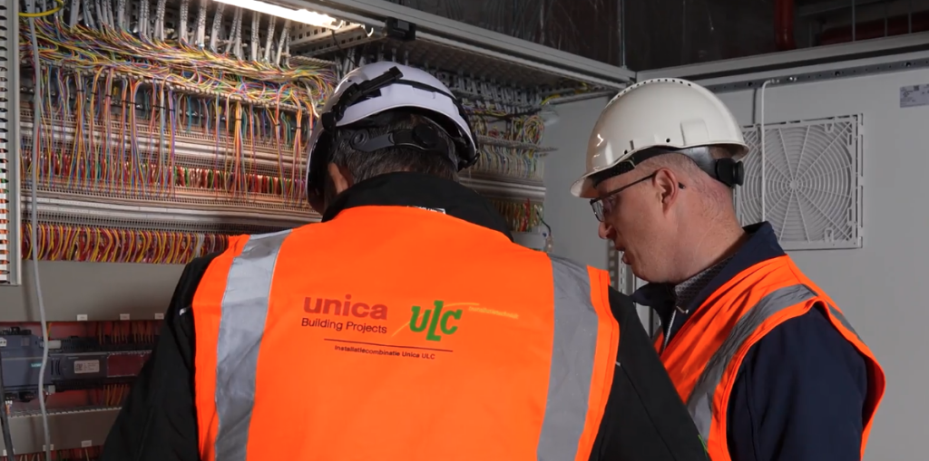 Technici werken aan kleurrijke bedrading in elektrische kast.