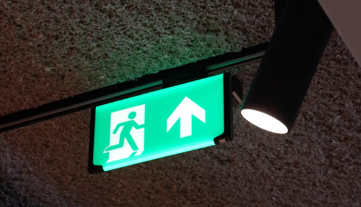 Groen verlicht nooduitgangsbord naar boven gericht.